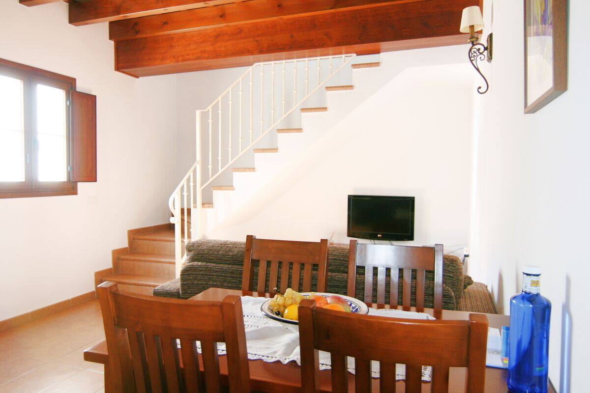 A dining area with a wooden table, chairs, and a television.