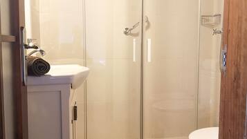 A bathroom with a glass-enclosed shower, a white sink, and a toilet.