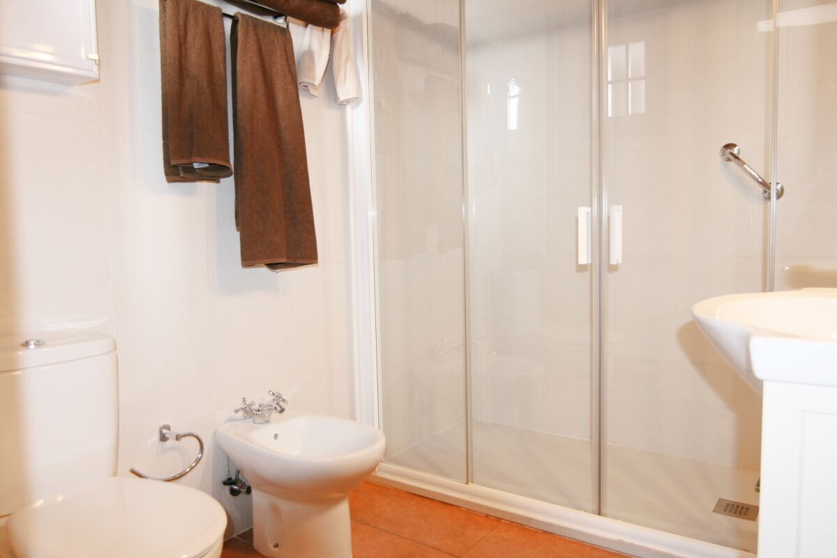 A bathroom with a toilet, bidet, and glass-enclosed shower.