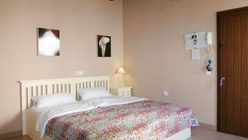 Un dormitorio con cama, mesita de noche, lámpara y puerta de madera.