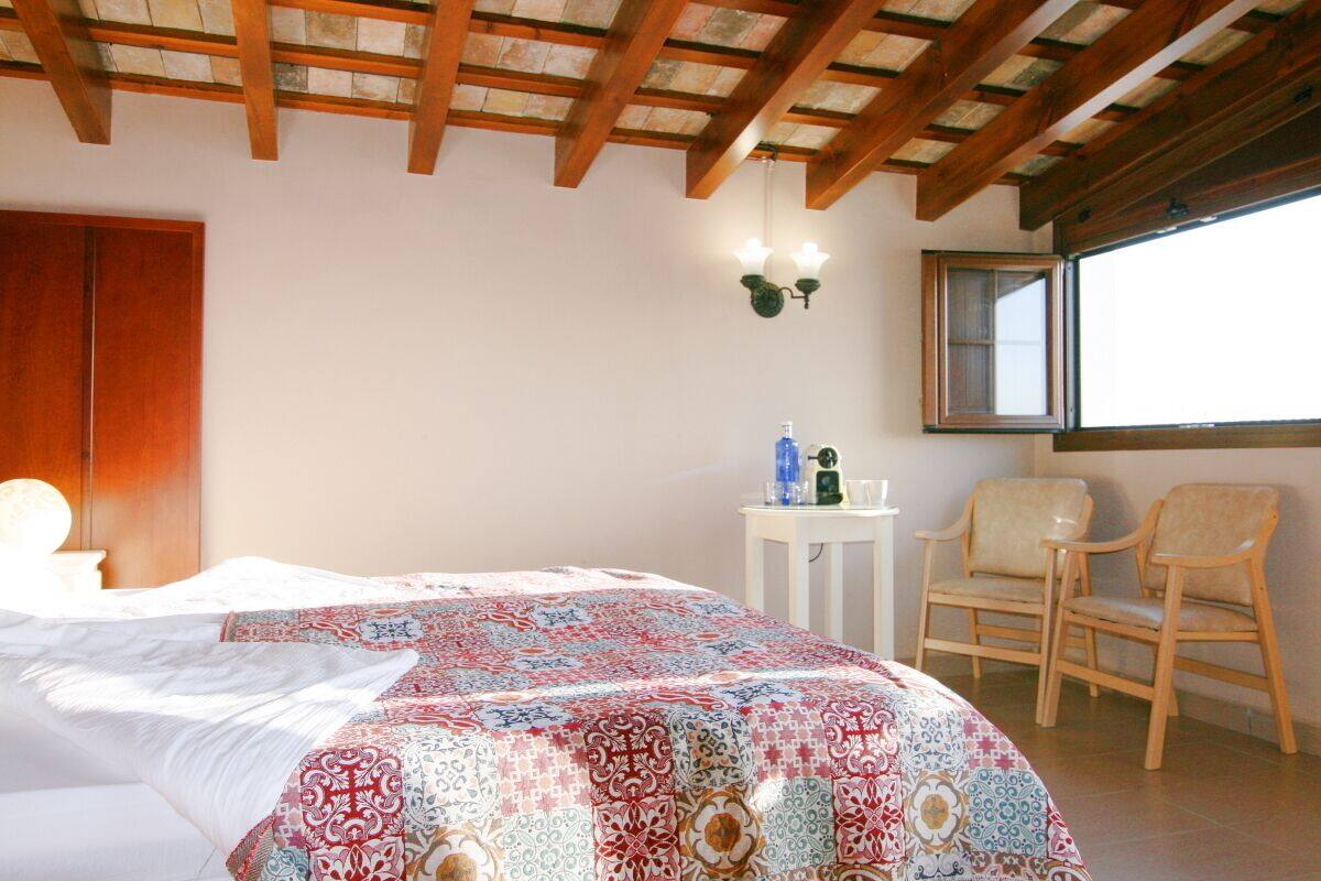 A bedroom with a bed, a window, and two chairs.