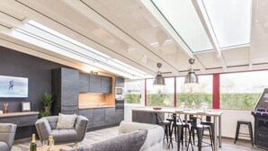 A modern kitchen with a built-in oven and microwave, a dining area with bar stools, and a large window offering a view of greenery.