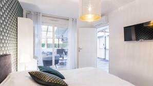 A modern hotel room with a large bed, a ceiling light, and a TV mounted on the wall.