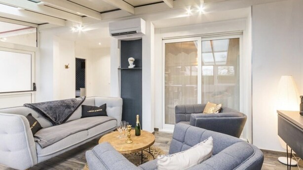 A modern living room with grey sofas, a coffee table, and a bookshelf.
