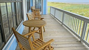 Een houten terras met zitplaatsen buiten en uitzicht op het strand.