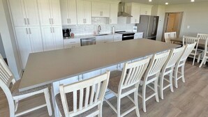 Een ruime keuken met witte kasten, een groot eiland met zitplaatsen en moderne apparatuur.