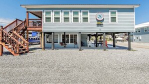 A two-story building with a covered porch, a staircase, and a sign indicating it is a marina.