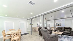 A spacious living area with a dining table and chairs, a gray sofa, and a coffee table.