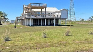 Una casa grande con un balcón y una torre de comunicaciones alta cerca.