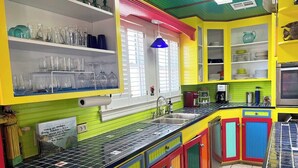 Una cocina con armarios de colores, un lavamanos y diversos utensilios de cocina.