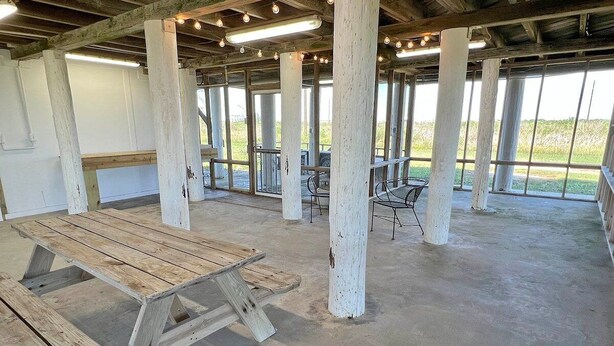 Un espacio interior con suelo de hormigón, bancos de madera y una mesa.