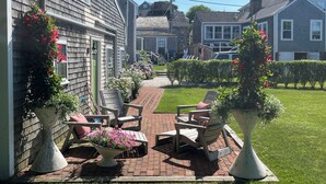 A patio with outdoor furniture and potted plants, a brick pathway, and a residential neighborhood in the background. - Renovated 2024, Blocks From the Inner Harbor/ Downtown - King, Twins, Pull out. (Nantucket)