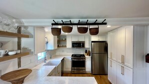A modern kitchen with white cabinetry, a stainless steel refrigerator, and a wooden island. - Renovated 2024, Blocks From the Inner Harbor/ Downtown - King, Twins, Pull out. (Nantucket)