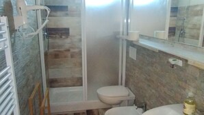 Une salle de bain avec une douche à parois de verre, des toilettes et un lavabo.