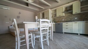 A kitchen with a dining table and chairs, light-colored cabinets, and a brick backsplash. - Colombaia, one-bedroom terraced house (Cecina)