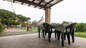 Eine Terrassengaststätte mit Tisch und Stühlen, einer Hängematte und Blick auf die Umgebung.