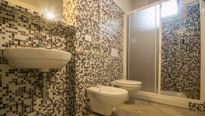 A bathroom with a mosaic tile wall, a sink, a bidet, and a shower with a glass door. - Limonaia , one-bedroom terraced house (Cecina)