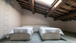 A room with two beds, a skylight, wooden beams, and a ladder. - Macine, two-bedroom terraced house (on two floors) (Cecina)