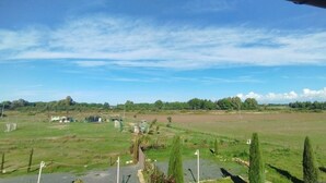 Ländliche Landschaft mit offenen Feldern, wenigen Gebäuden und blauem Himmel.