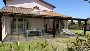 A house with a covered patio area, outdoor seating, and a garden. - Fienile building, two-bedroom terraced house (Cecina)