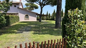 A house with a paved driveway, a wooden fence, and a well-maintained lawn. - Fienile building, two-bedroom terraced house (Cecina)