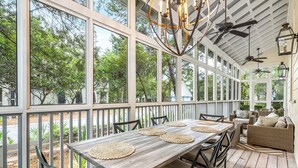 A covered patio with a wooden table and chairs, a sofa, and a ceiling fan. - Lake District Luxury: 6-Bedroom Retreat with WaterColor Beach Club Access, Bikes, and Electric Cart! (Santa Rosa Beach)
