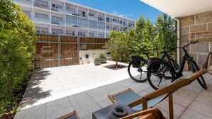 A courtyard with a wooden fence, potted plants, and bicycles. - The 98 Place (Carcavelos)