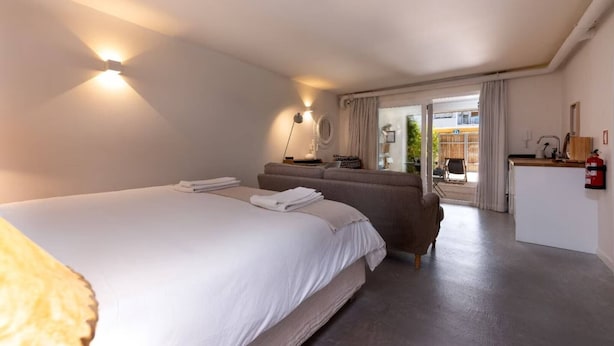 A hotel room with a large bed, a sofa, a desk, and a view of the outdoors. - The 98 Place (Carcavelos)
