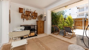 A cozy living room with a white sofa, a wooden cabinet, and a small table. There are two chairs and a rug on the floor. - The 98 Place (Carcavelos)