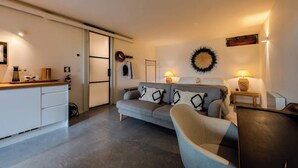 A modern living room with a grey sofa, a wooden coffee table, and a small side table with a lamp. - The 98 Place (Carcavelos)