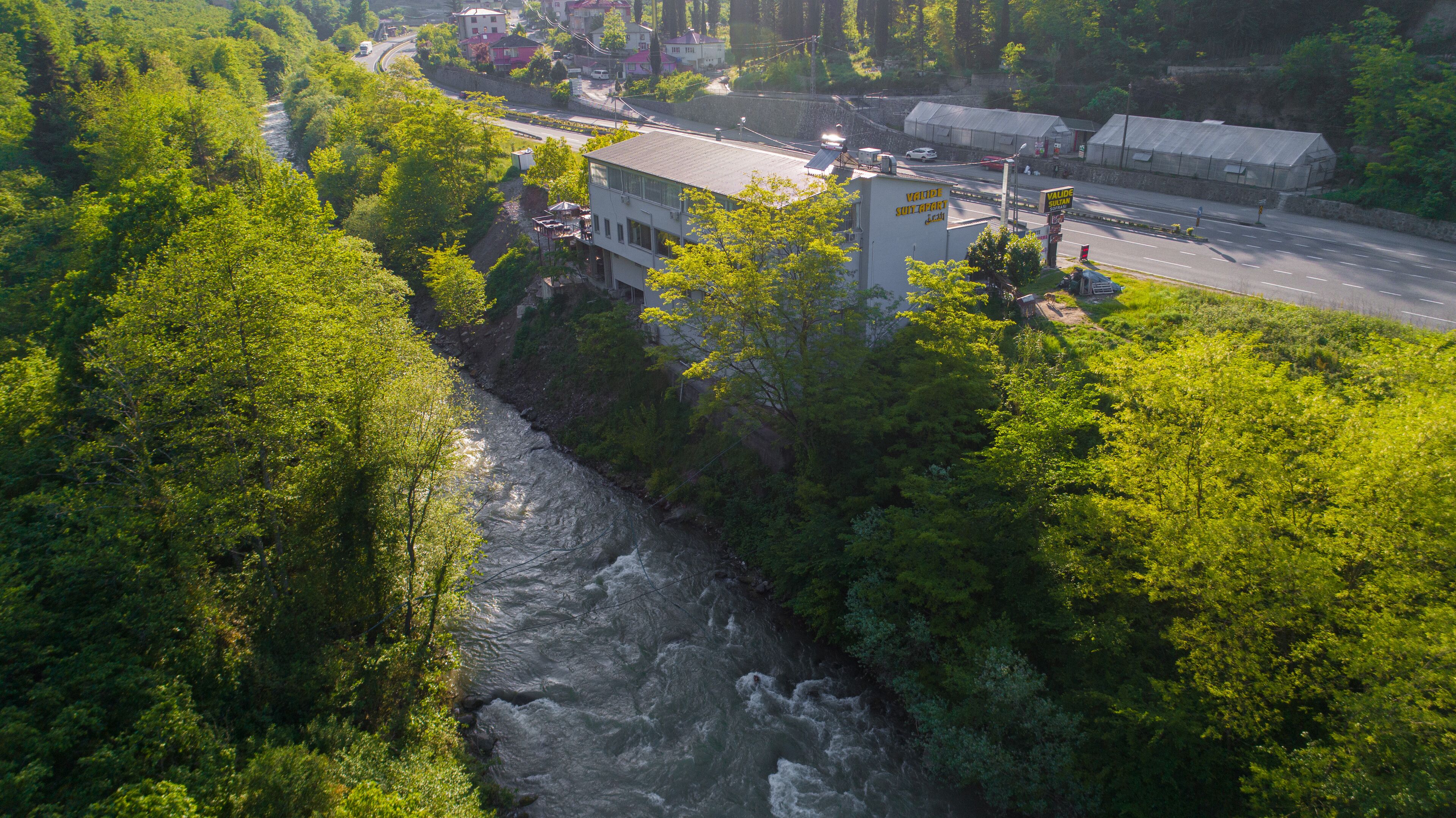 Un río serpenteando por un área boscosa con edificios y una carretera cerca.