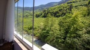 Una habitación con un amplio ventanal que da a un valle verde y exuberante y un río.