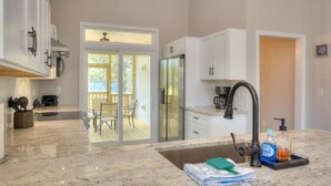 Eine moderne Küche mit weißen Schränken, einem Edelstahlkühlschrank, einem schwarzen Wasserhahn und einer Arbeitsplatte mit Reinigungsmitteln.