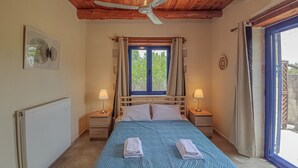 Una camera da letto con un letto, due lampade da comodino, una ventola a soffitto, una finestra con tende e un termosifone.