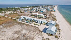 Ein Luftbild eines Küstenresorts mit Strandhäusern, einem Schwimmbad und einem Sandstrand.