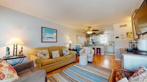 A cozy living room with a sofa, armchairs, and a dining area. A kitchen is visible in the background. - Gulf view, family-friendly townhome (Gulf Shores)