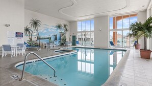An indoor swimming pool with clear blue water, surrounded by lounge chairs and a mural of palm trees. - Avalon 507-Oceanside 140th St, Free WiFi, Pool, Elev, W/D, AC (Ocean City)