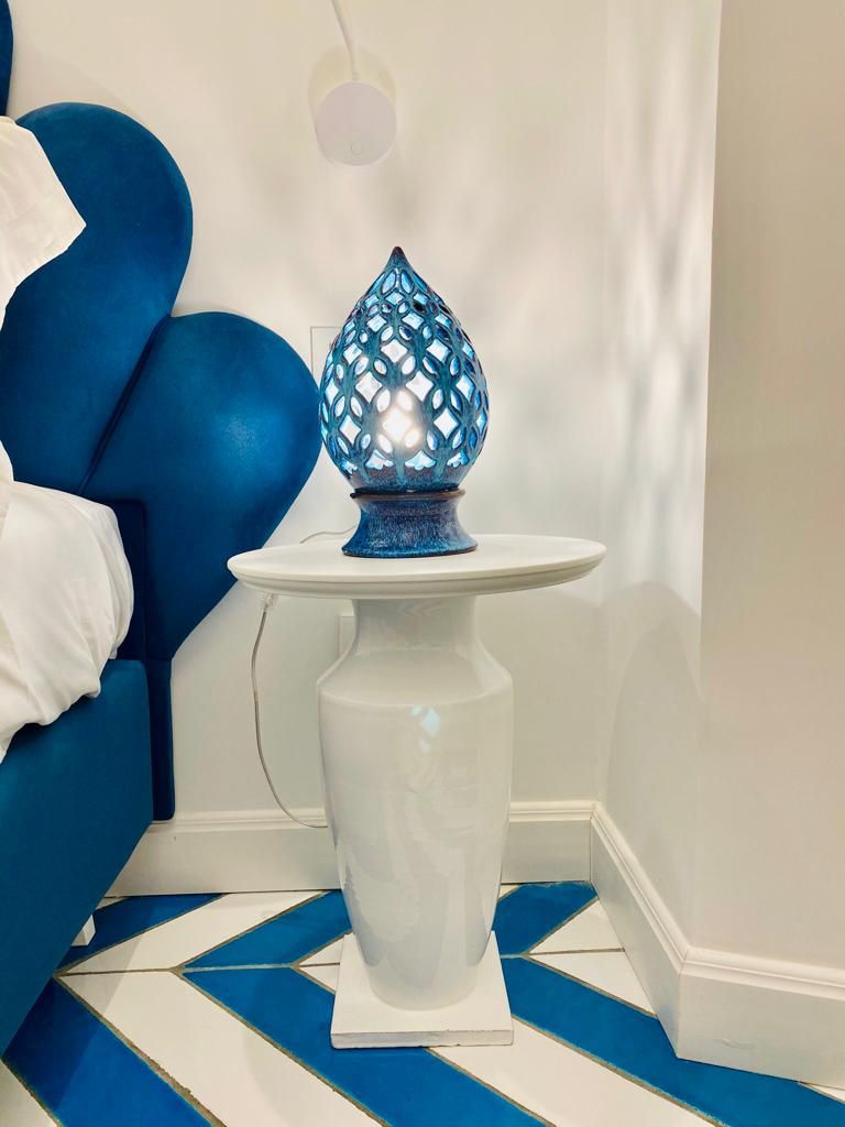 A white pedestal table with a blue decorative lamp.