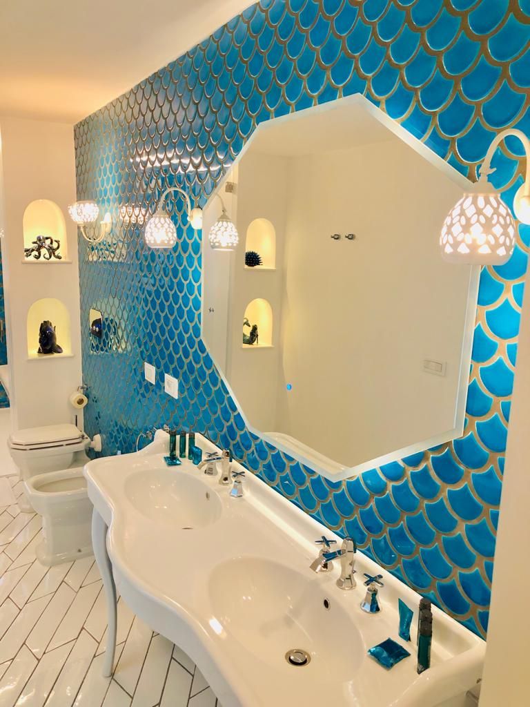 A bathroom with a large mirror, two sinks, and a blue patterned wall.