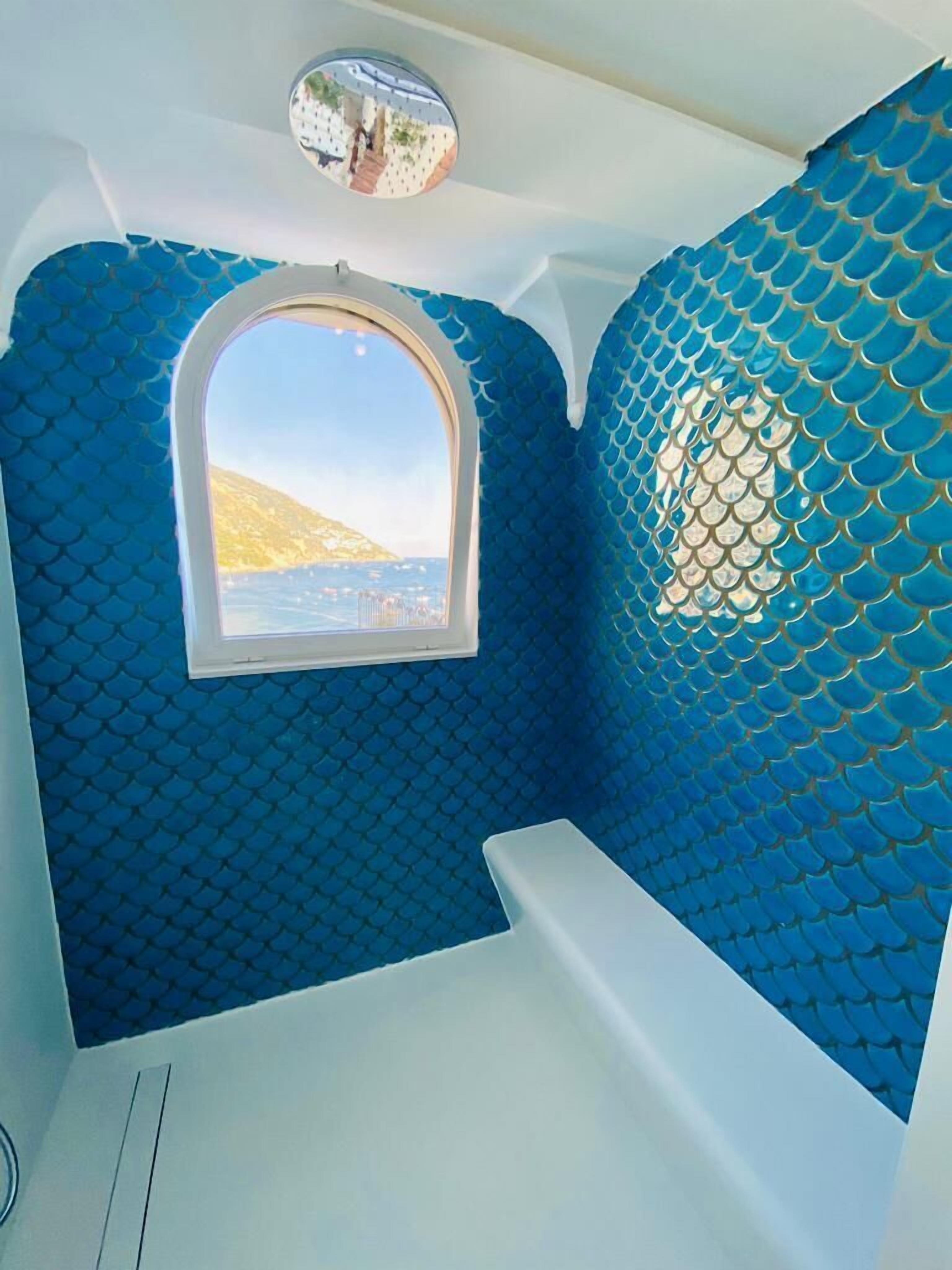 Ein Zimmer mit einem Rundfenster, einer blauen Wand mit Muster und einer weißen Decke.