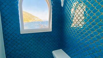 Ein Zimmer mit einem Rundfenster, einer blauen Wand mit Muster und einer weißen Decke.