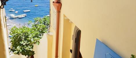 A narrow stairway leading to a balcony overlooking a sea with boats, a lamp, and a sign reading "Villa Lujuria".