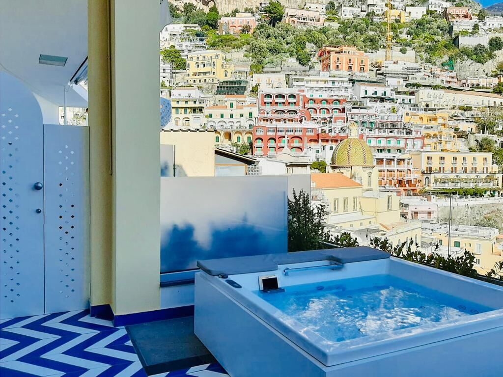 A modern bathroom with a large bathtub and a view of a hillside town.