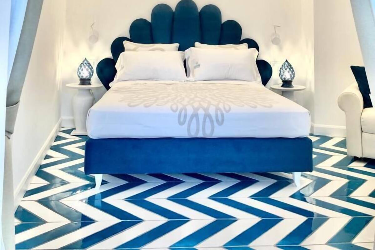 Ein modernes Schlafzimmer mit einem großen Bett, einem geometrisch gemusterten Boden und einer Kandelaber.