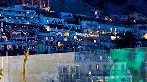 Zona de piscina con toallas que indican "Villa Diamond Luxury Suite" y vista a un pueblo en la ladera por la noche.