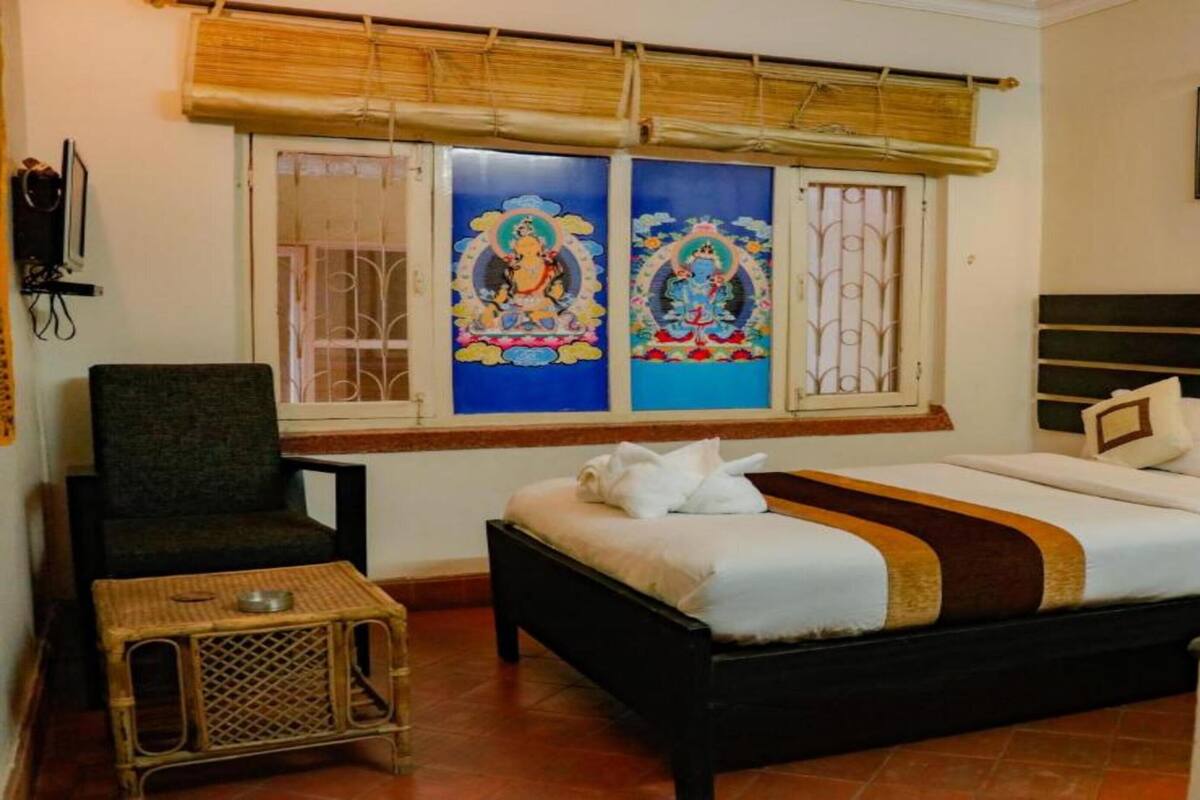 A room with a bed, a chair, a small table, and a window with decorative glass panels.