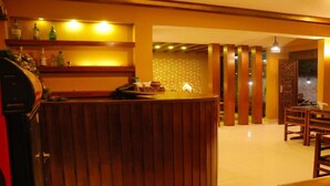 A bar area with wooden furnishings, a brick wall, and a dining area with chairs and tables. - MeroStay 124 (Kathmandu)