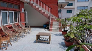 A balcony with wicker chairs, a small table, and potted plants. - MeroStay 124 (Kathmandu)