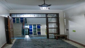 A hallway with a patterned carpet, a chandelier, and a door leading to a room with blue and white patterned glass. - MeroStay 124 (Kathmandu)