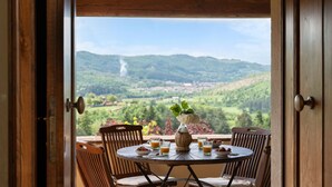 Una puerta de madera abierta que da a un comedor con una mesa dispuesta para dos, con vistas a un paisaje montañoso.